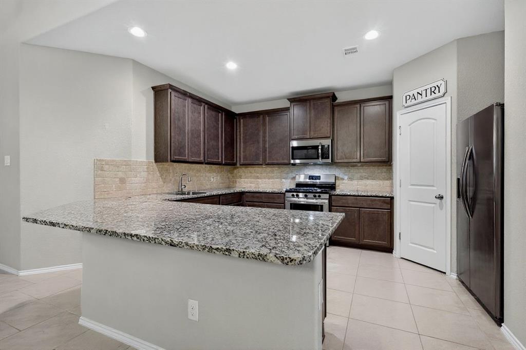 22038 Pheasant Bend Lane Porter, TX 77365 - Photo 6 of 25 a kitchen with granite countertop wooden cabinets a refrigerator and a sink
