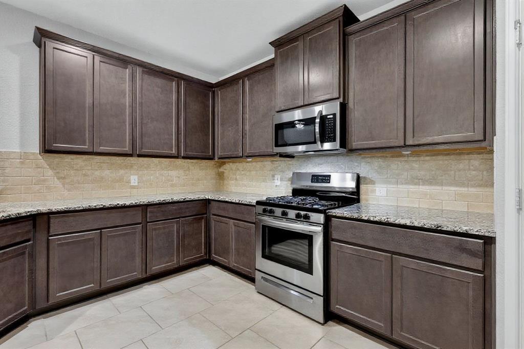 22038 Pheasant Bend Lane Porter, TX 77365 - Photo 7 of 25 a kitchen with granite countertop wooden cabinets stainless steel appliances and a sink