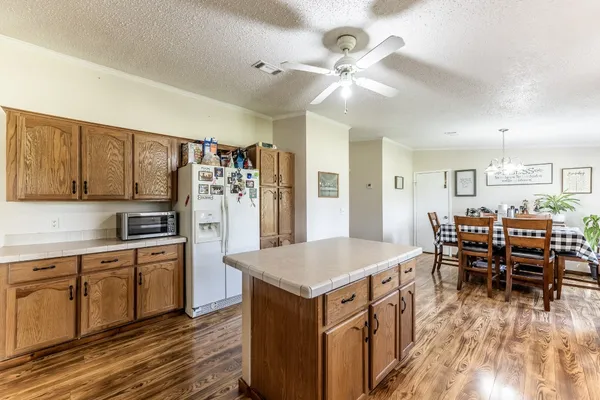 a open kitchen with stainless steel appliances granite countertop a stove top oven a refrigerator a dining table and chairs with wooden floor