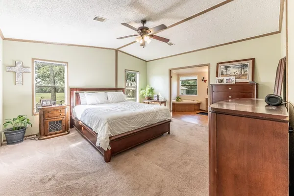 a spacious bedroom with a bed couch chandelier and a window