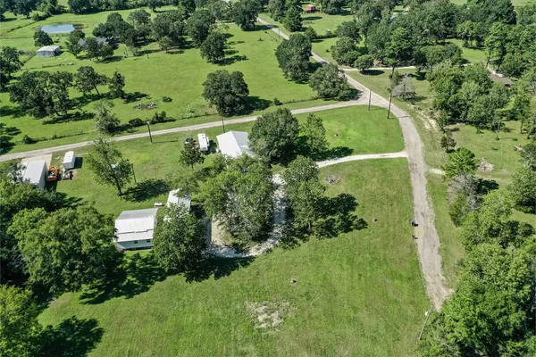 an aerial view of residential houses with outdoor space and trees all around