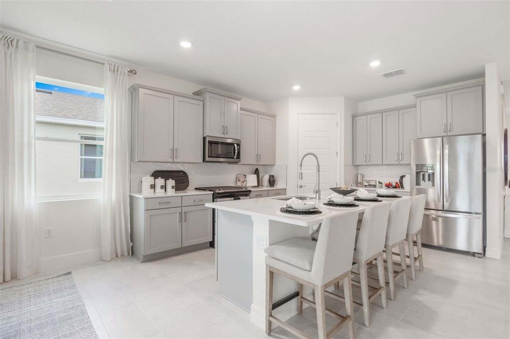 3952 Kennebunk Loop Mount Dora, FL 32757 - Photo 15 of 36 a kitchen with white cabinets and stainless steel appliances