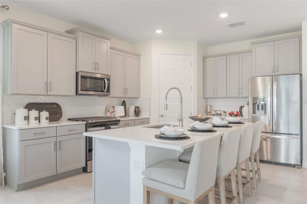 3952 Kennebunk Loop Mount Dora, FL 32757 - Photo 16 of 36 a kitchen with stainless steel appliances granite countertop a sink a stove a refrigerator and white cabinets