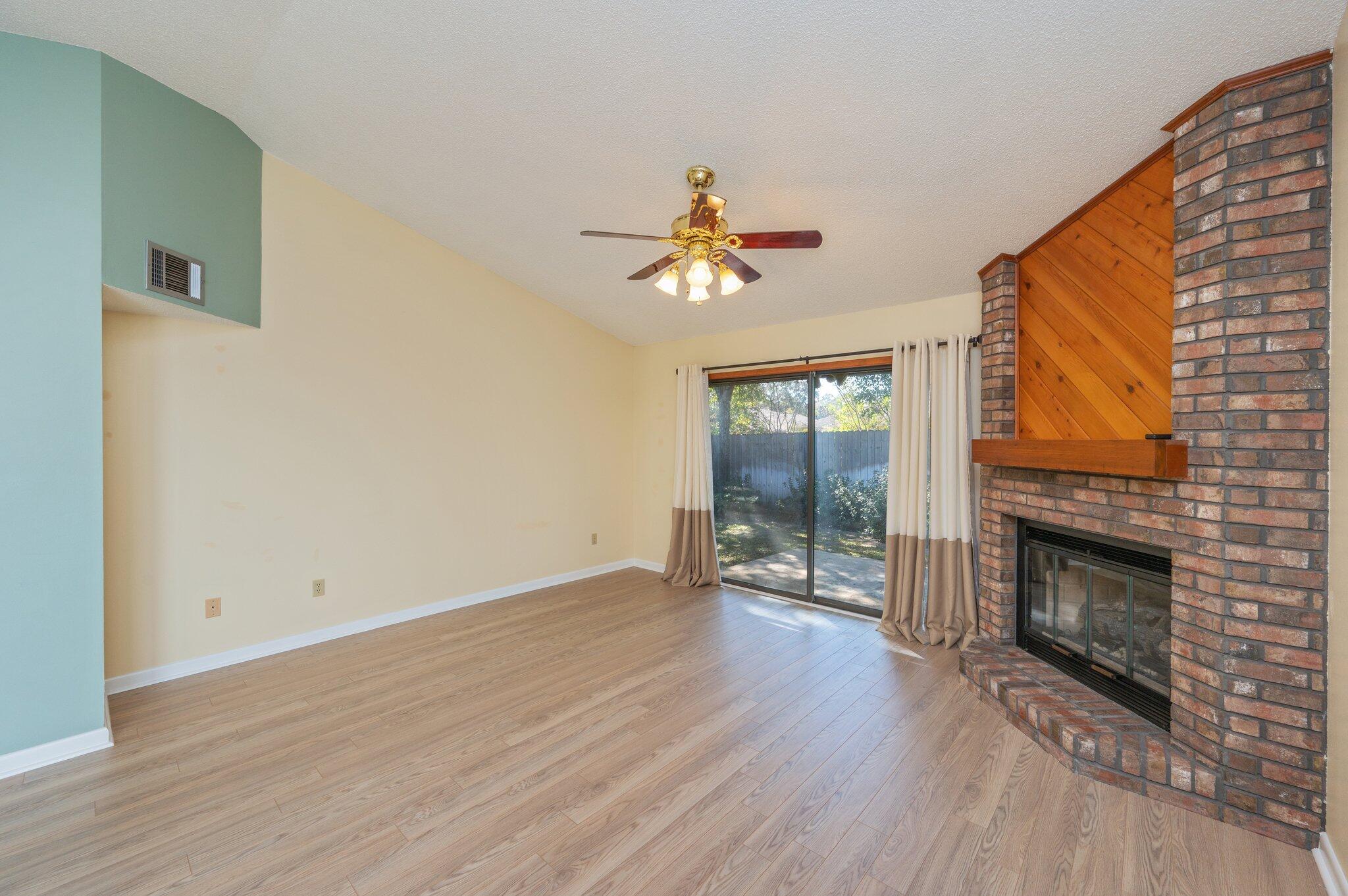 101 Cedar Ridge Way Niceville, FL 32578 - Photo 6 of 33 an empty room with wooden floor a fireplace and a window
