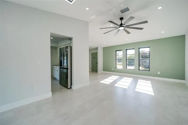 a large kitchen with granite countertop a stove a sink a refrigerator and white cabinets with wooden floor