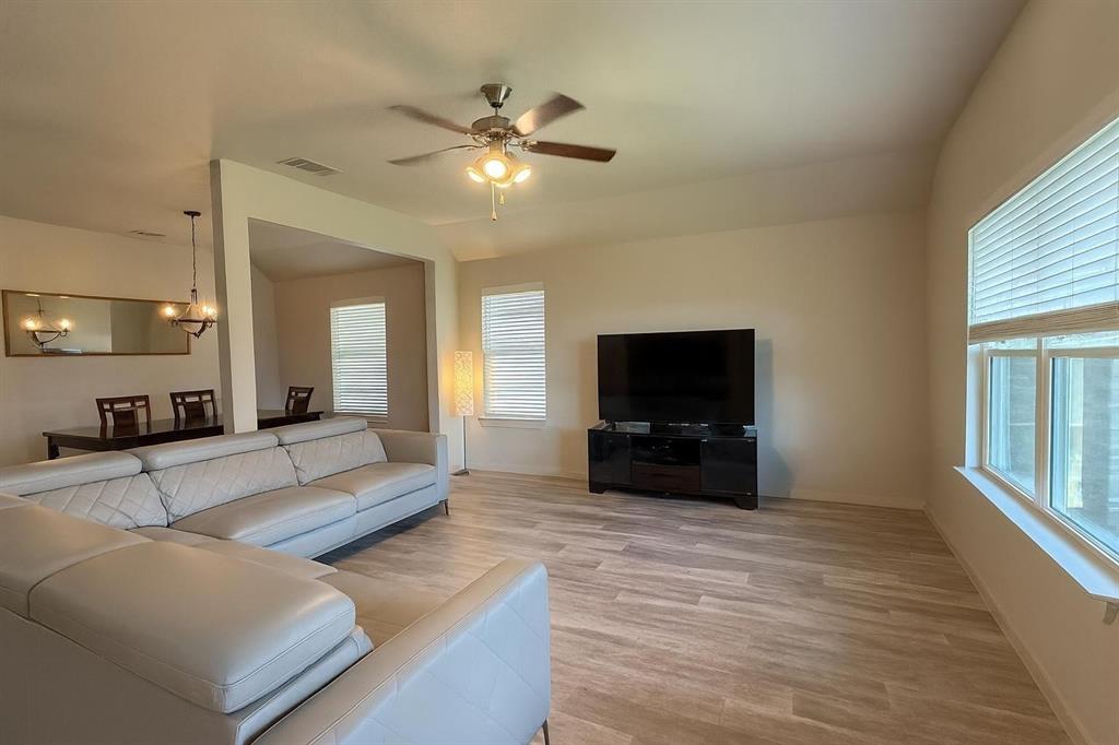 5641 Durst Lane Forney, TX 75126 - Photo 3 of 10 Living room with light wood finished floors, a ceiling fan, vaulted ceiling, and a chandelier