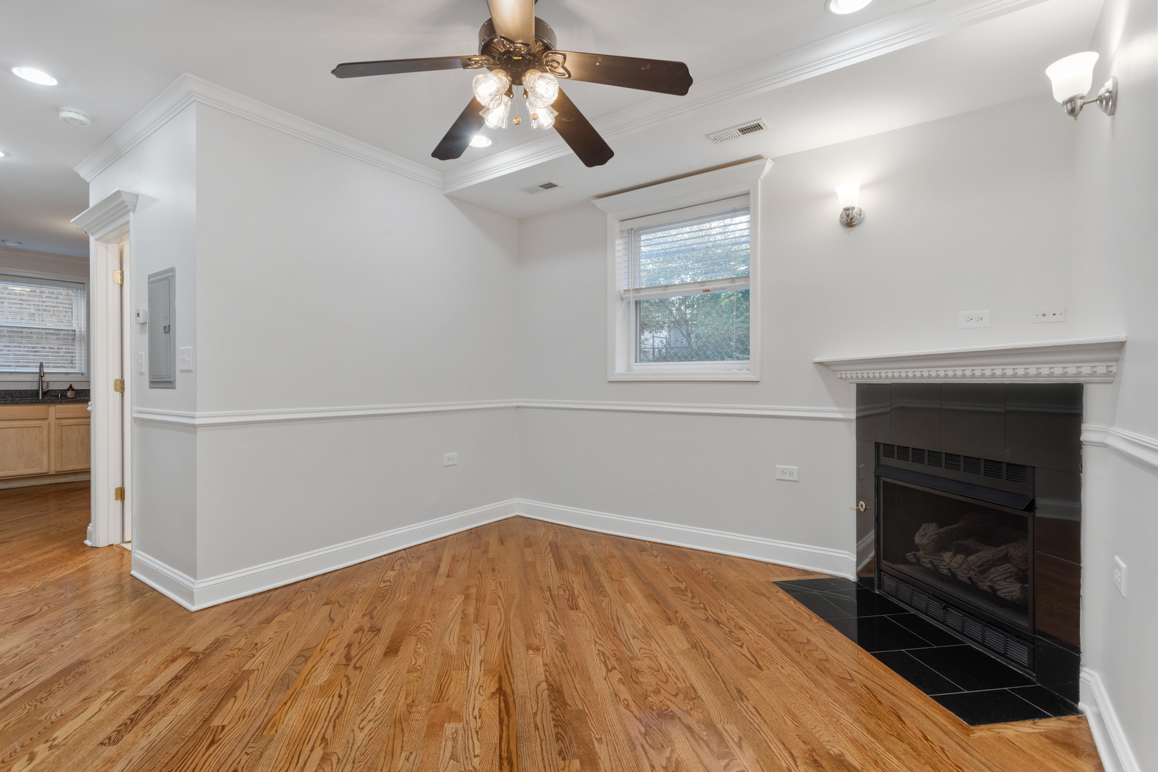 4110 North Keystone Avenue, Unit 1N Chicago, IL 60641 - Photo 2 of 15 an empty room with wooden floor a ceiling fan a fireplace and windows in a room