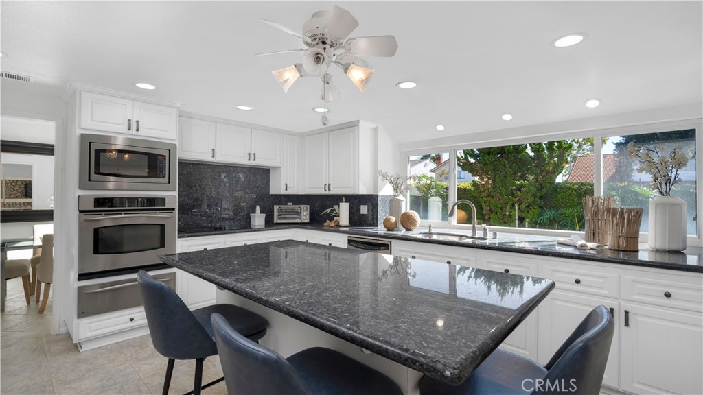 7 Nantucket Irvine, CA 92620 - Photo 14 of 55 a large kitchen with granite countertop a stove a sink a counter top space appliances and cabinets