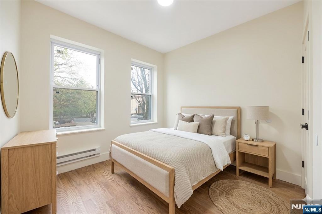 10 School Street, Unit 2 Passaic, NJ 07055 - Photo 4 of 11 a bedroom with a bed a mirror and a window