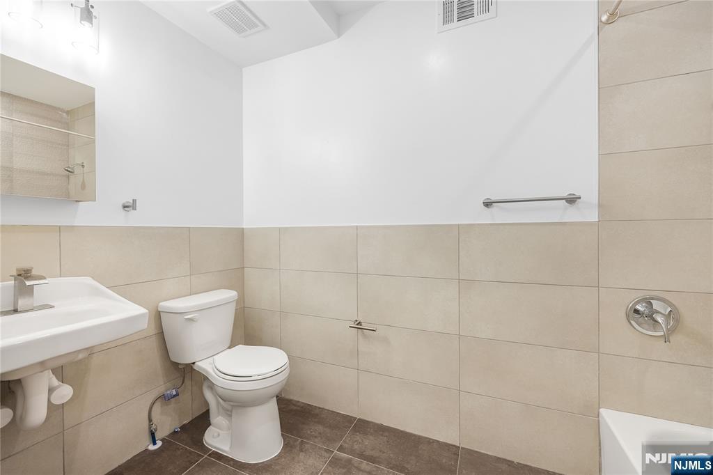 10 School Street, Unit 2 Passaic, NJ 07055 - Photo 7 of 11 a bathroom with a toilet sink and mirror