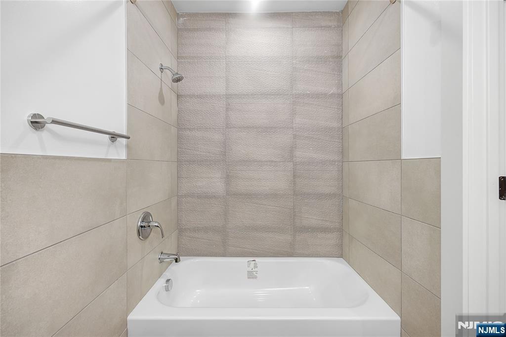 10 School Street, Unit 2 Passaic, NJ 07055 - Photo 8 of 11 a white bath tub sitting next to a white sink and vanity