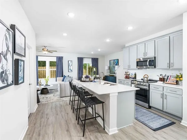 a kitchen with a sink a stove a refrigerator and white cabinets with wooden floor
