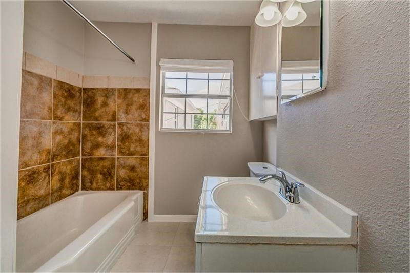 3502 Rosedale Street Houston, TX 77004 - Photo 13 of 17 Bright bathroom with a tiled tub-shower combo, modern vanity, and ample natural light from the window.