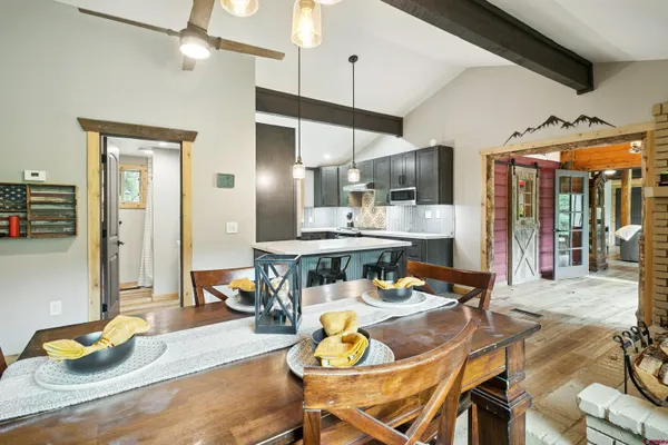 a dining room with stainless steel appliances kitchen island granite countertop a table chairs and a refrigerator