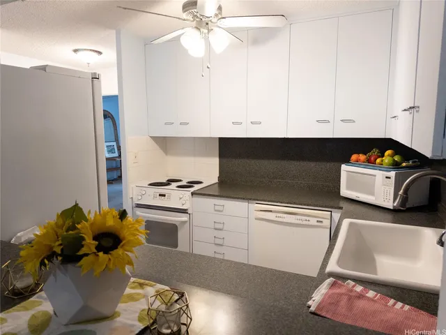 a kitchen with stainless steel appliances granite countertop a sink dishwasher stove and white cabinets