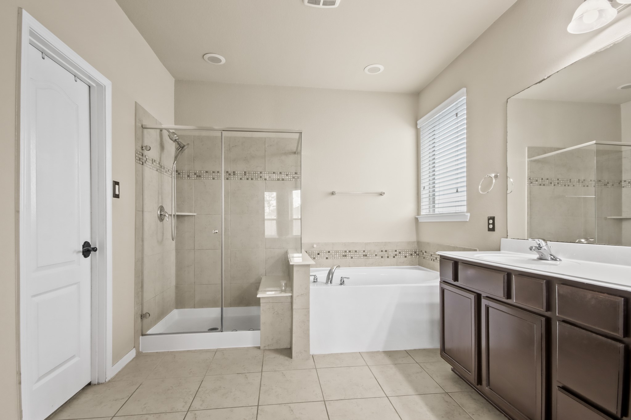 25407 Terrain Park Drive Spring, TX 77373 - Photo 19 of 33 Spacious primary bathroom featuring a clean, modern layout with elegant finishes. The room includes a glass-enclosed walk-in shower with tiled walls and decorative accent trim, alongside a relaxing soaking tub perfect for unwinding.