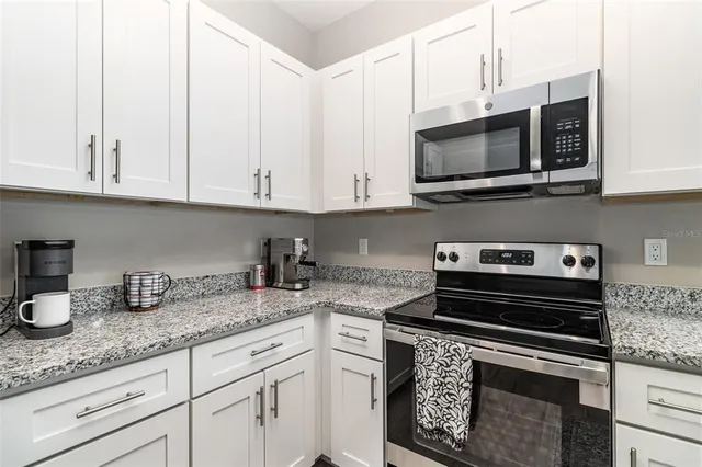 a kitchen with granite countertop white cabinets and stainless steel appliances