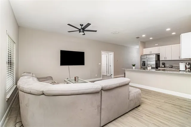 a living room with stainless steel appliances kitchen island furniture and a flat screen tv