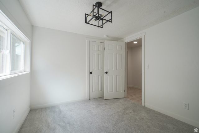557 Cook Street Ogden, UT 84404 - Photo 16 of 17 Bright room featuring light gray carpeting, white walls, and a modern geometric ceiling light fixture