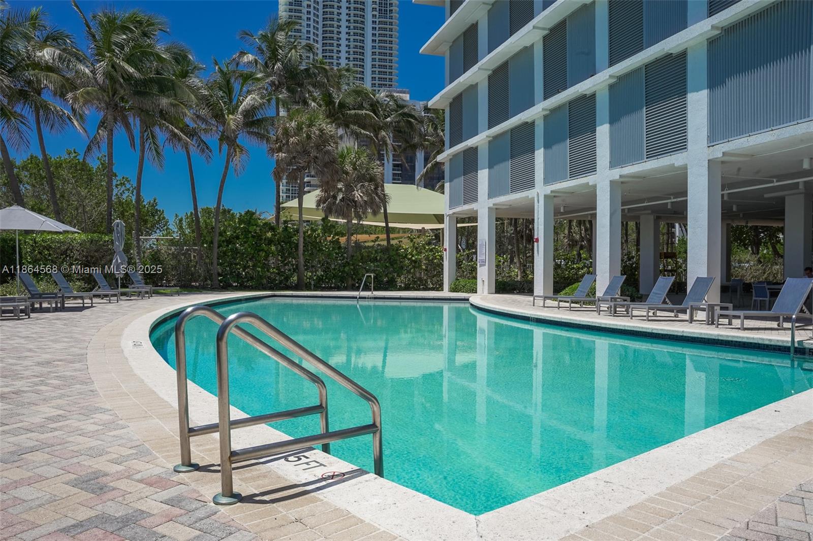 6515 Collins Avenue, Unit 1709 Miami Beach, FL 33141 - Photo 23 of 30 a view of a swimming pool with a lounge chairs