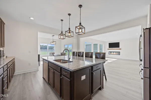 a kitchen with stainless steel appliances granite countertop a kitchen island a stove a sink a refrigerator and a wooden floor