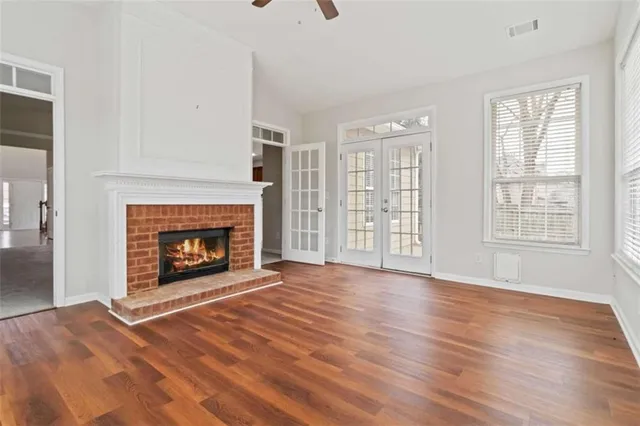a view of an empty room with wooden floor fireplace and a window