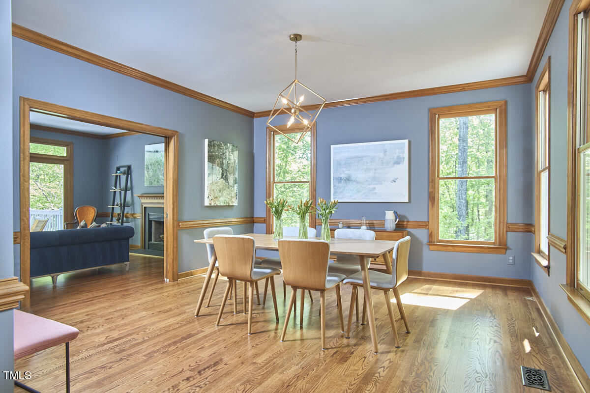 8407 Millers Bend Bahama, NC 27503 - Photo 16 of 77 a dining room with wooden floor a chandelier a glass table and chairs