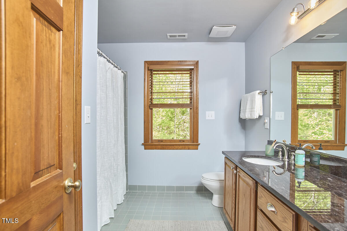 8407 Millers Bend Bahama, NC 27503 - Photo 53 of 77 a bathroom with a granite countertop sink toilet and mirror