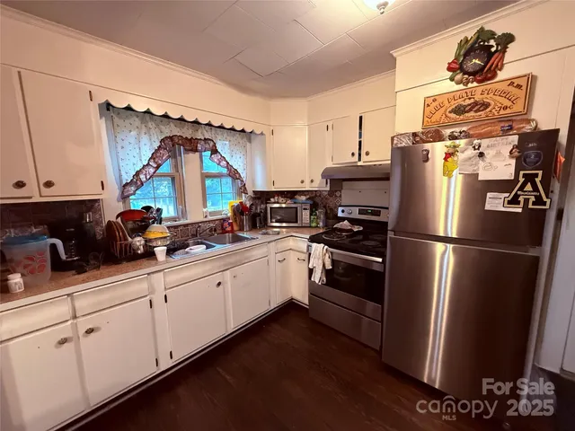 a kitchen with stainless steel appliances a refrigerator a sink a stove and white cabinets