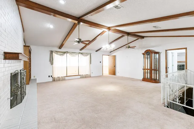 a view of an empty room with chandelier fan and a window