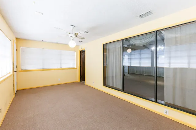 an empty room with windows and fan