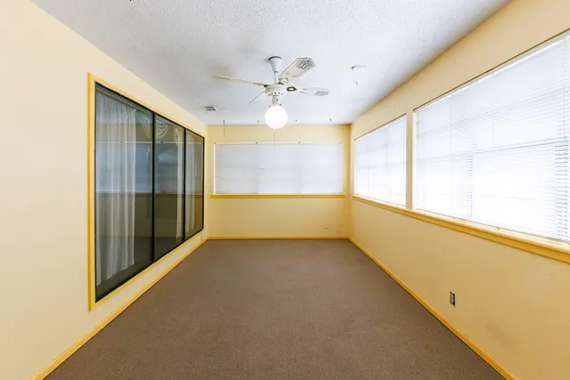 an empty room with windows and fan