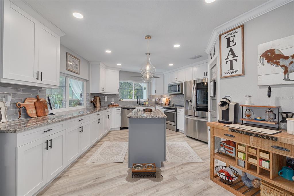1868 Overview Drive New Port Richey, FL 34655 - Photo 12 of 69 a kitchen with stainless steel appliances kitchen island granite countertop a refrigerator oven a sink dishwasher and white cabinets with wooden floor