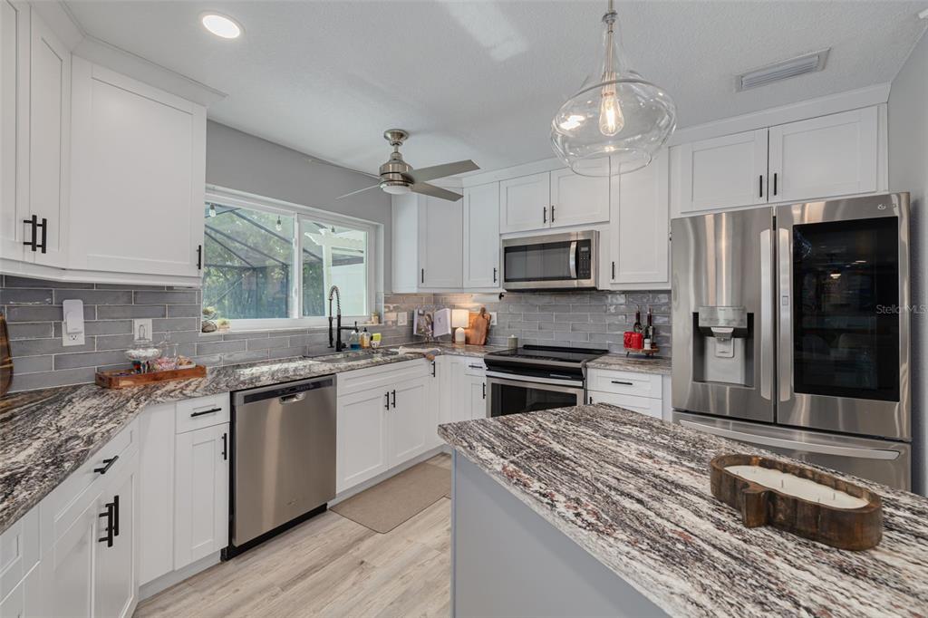 1868 Overview Drive New Port Richey, FL 34655 - Photo 13 of 69 a kitchen with stainless steel appliances granite countertop a stove top oven a refrigerator a sink and dishwasher with wooden floor