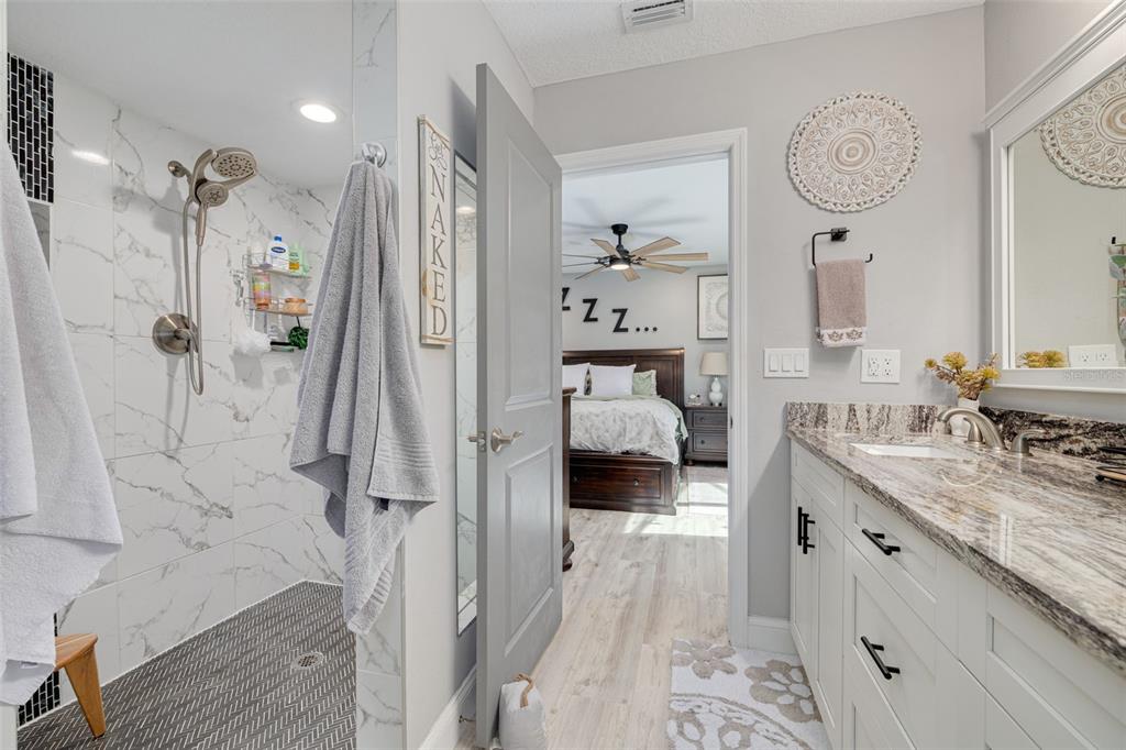 1868 Overview Drive New Port Richey, FL 34655 - Photo 28 of 69 a en suite bathroom with a granite countertop double vanity sink a mirror a vanity and shower