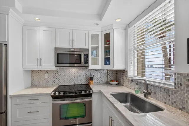 a kitchen with granite countertop white cabinets and stainless steel appliances