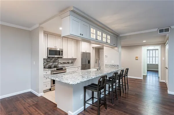 a kitchen with stainless steel appliances kitchen island granite countertop a kitchen island hardwood floor and a sink