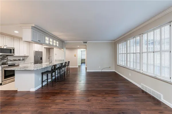 a kitchen with stainless steel appliances granite countertop a stove top oven a sink dishwasher a dining table and chairs with wooden floor