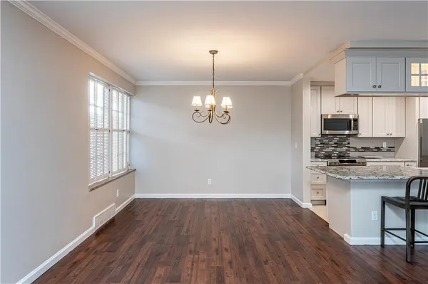 a kitchen with granite countertop wooden floors appliances and cabinets