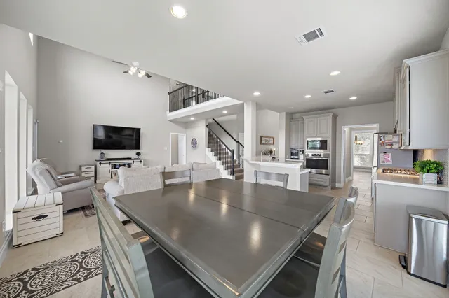 a living room with stainless steel appliances a table and chairs in it