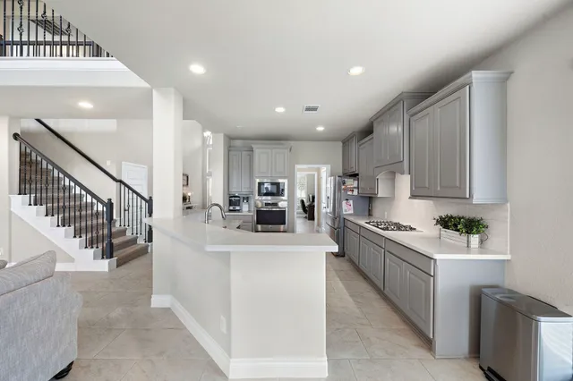 a kitchen with stainless steel appliances kitchen island granite countertop a sink and a refrigerator