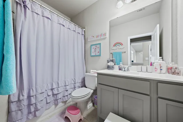 a bathroom with a toilet sink vanity and mirror