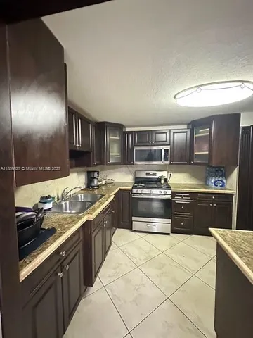 a large kitchen with stainless steel appliances granite countertop a sink and stove top oven