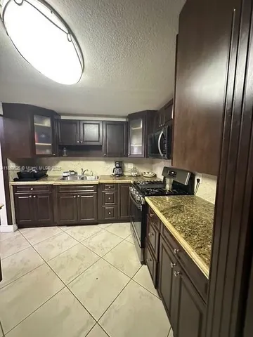 a kitchen with stainless steel appliances granite countertop a stove a sink and a microwave