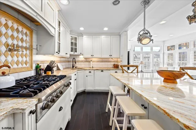 a kitchen with stainless steel appliances granite countertop a stove a sink dishwasher and white cabinets with wooden floor