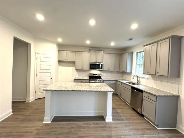 a large kitchen with stainless steel appliances granite countertop a large counter top a sink a stove and a refrigerator