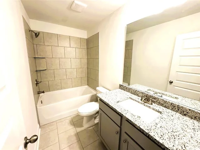 a bathroom with a granite countertop sink toilet and bathtub