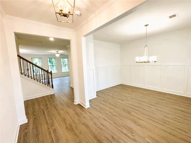 a view of a room with wooden floor staircase and a kitchen