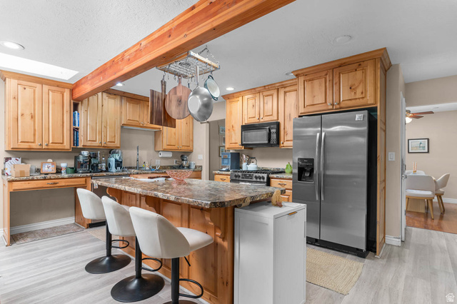 1489 North 400 West Bountiful, UT 84010 - Photo 8 of 47 Kitchen featuring a central island with bar seating, wood-finish cabinetry, granite-style countertops, stainless steel appliances, and light wood-finish flooring