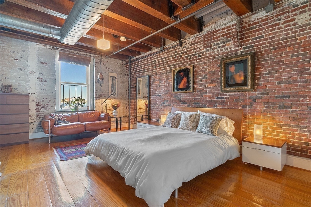 59 Commercial Wharf, Unit 1 Boston, MA 02110 - Photo 11 of 19 a spacious bedroom with a bed and wooden floor